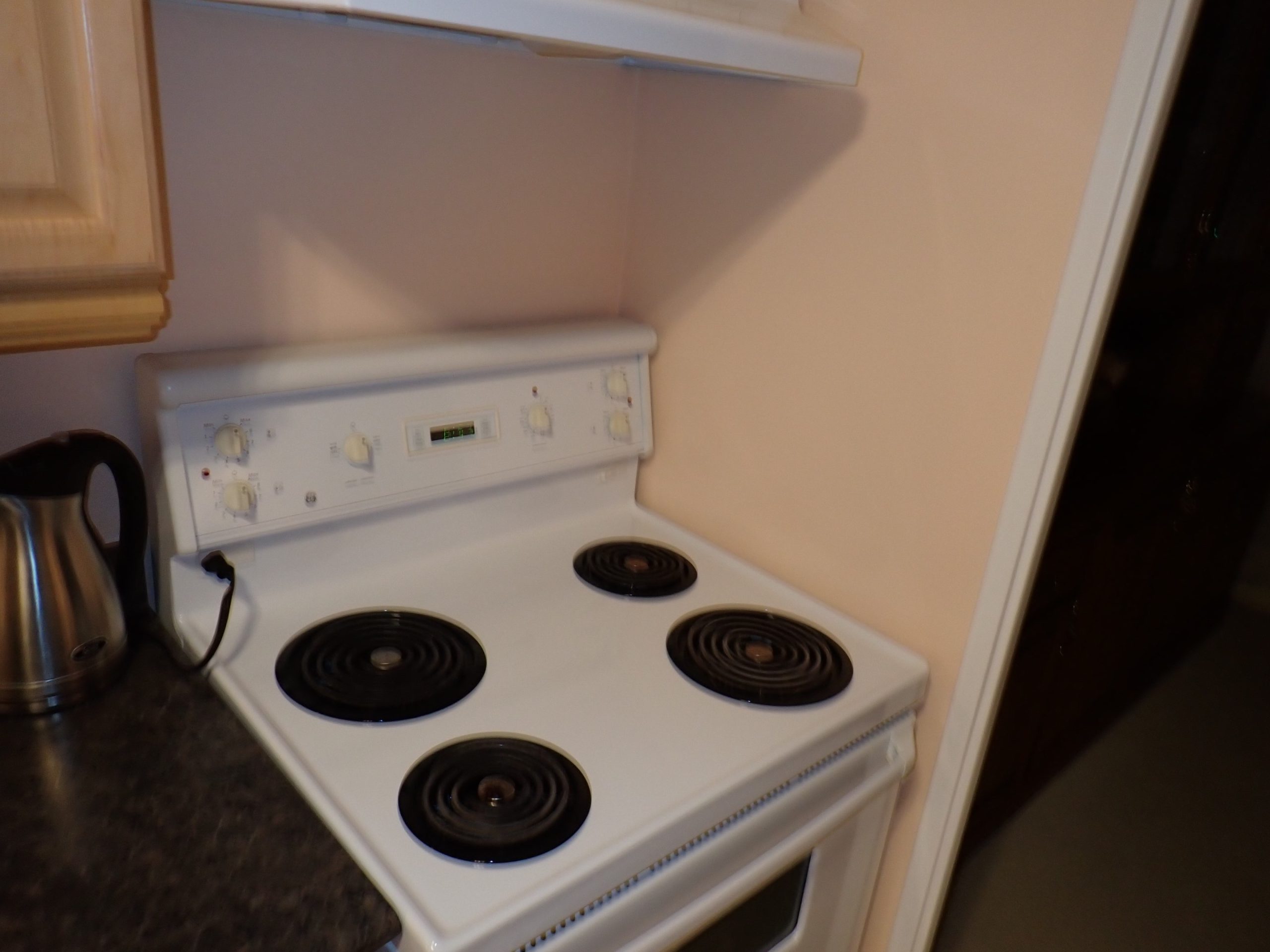 The lack of fire protection on the drywall represents a code violation when using a highly radiant stovetop, such as an electric coil range.